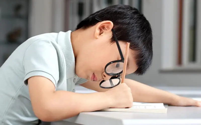 Ngồi học sai tư thế, đeo kính không đúng độ có thể làm nặng thêm loạn thị ở trẻ