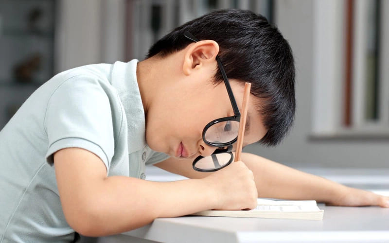 Ngồi học sai tư thế, đeo kính không đúng độ có thể làm nặng thêm loạn thị ở trẻ