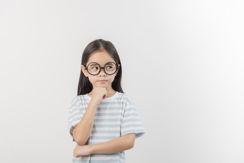Child wearing glasses – a common early sign of refractive errors like myopia or astigmatism, requiring regular eye exams.